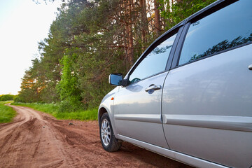 A passenger car standing on the side of a dirt clay road going to the horizon.