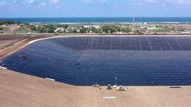 Water reservoir construction site with newly installed plastic lining sheets, Aerial view.