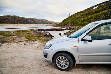 Fototapeta na wymiar Small car standing on the side of road near wate of lake, river, fiord, sea and ocean.