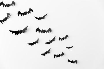 halloween, decoration and scary concept - flock of black paper bats flying over white background