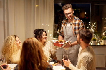 holidays, celebration and people concept - happy smiling friends having christmas dinner at home in...