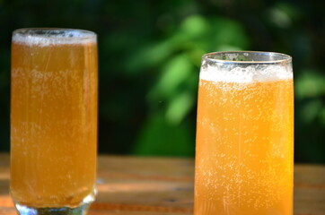 two glasses filled with ice-cold beer standing on a table at the beach or on a table in a cafe or picnic, meeting with friends in nature