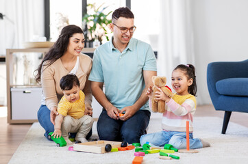 family and people concept - happy mother, father, little daughter and baby son playing with wooden toys at home