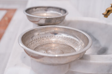Traditional Turkish bath hammam or hamam with marble benches and sinks, taps for hot and cold water and metal bowls