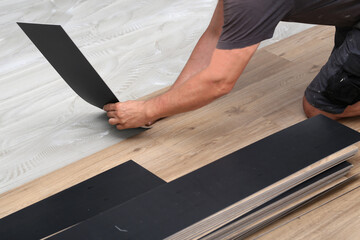 The worker installing new vinyl tile floor