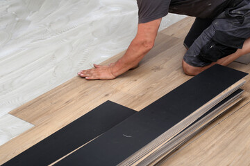 The worker installing new vinyl tile floor