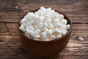 Fresh cottage cheese grain in a wooden bowl. Curd in granules with cream. Wooden rustic background. Copy space.