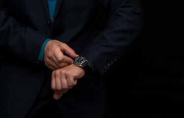 A wristwatch on the hand of a business man in a dark blue jacket.