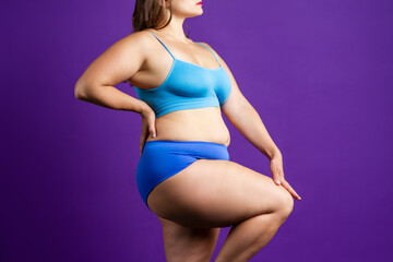 Plus size model in blue lingerie, fat woman with thick thigh on purple background