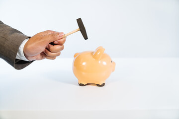 side view of a hand with a hammer breaking a ceramic piggy bank on a white background