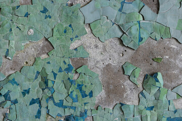 Peeling paint on the wall. Old concrete wall with cracked flaking paint. Weathered rough painted surface with patterns of cracks and peeling. High resolution texture for background and design. Closeup