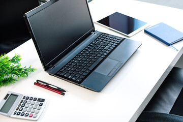 office table with a laptop, calculator, notebook, tablet, pens
