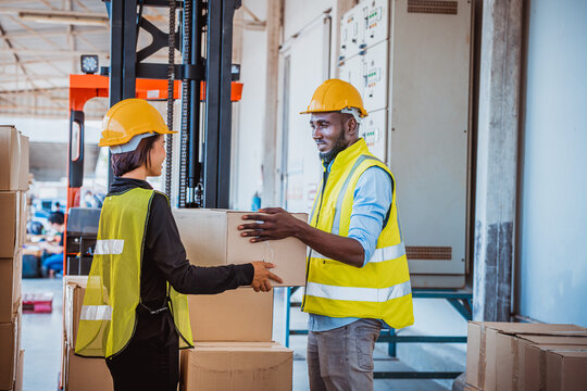Industry workers helping to move produce boxes for folklife truck to keep on factory warehouse,they wearing safety uniform to work.