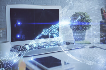 Computer on desktop in office with technology theme hologram. Double exposure. Tech concept.