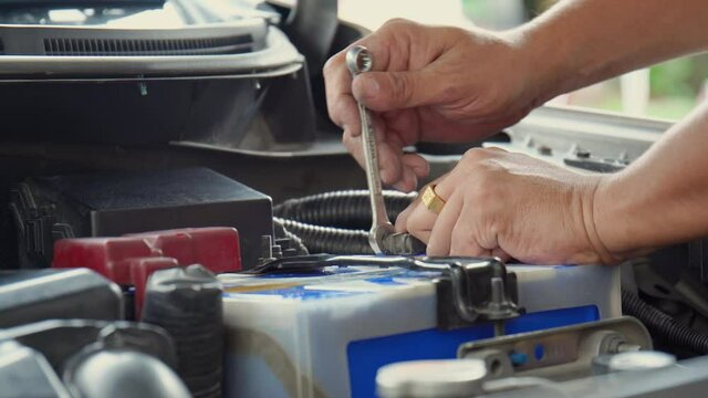 Close up of Mechanic engineer fixing car battery, technician man working to install battery with wrench