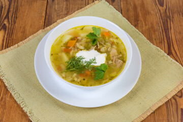 Rassolnik portion seasoned with sour cream on old rustic table