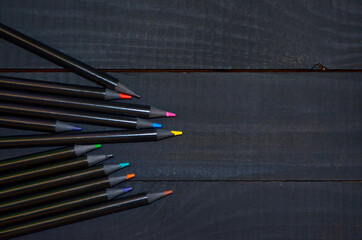 beautiful black pencils with colored lead on a black background, black colored pencils, on black background, black on black background