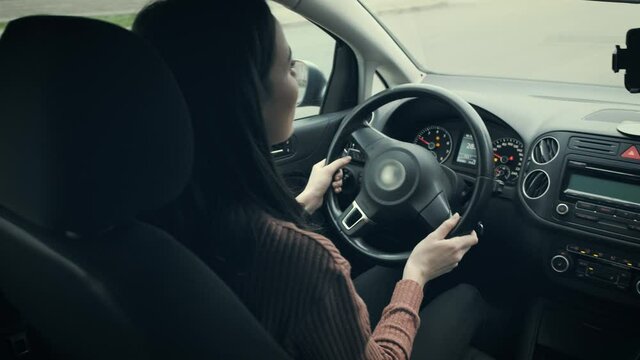 Girl, brunette, driving a car. View from the salon. The vehicle is in motion.