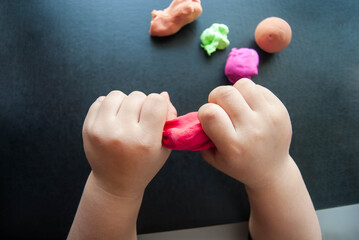 children's hands sculpt a multi-colored mass for modeling, plasticine. Leisure for children, children's creativity