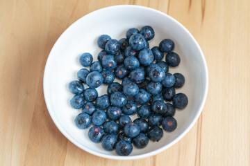 Fresh blueberries in a white bowl on a wooden table