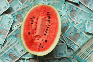 Half a watermelon on a background of blue Indian rupees.