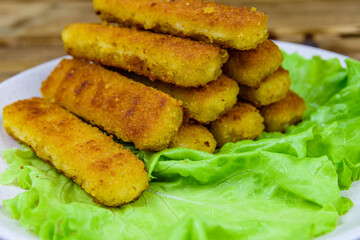 Baked fish sticks and lettuce leaves in a plate