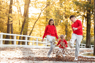 Fototapeta premium Mother, father and little daughter having fun in the autumn park. Young family spending time together on vacation, outdoors. The concept of family holiday.