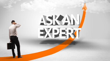 Fototapeta premium Rear view of a businessman standing in front of ASK AN EXPERT inscription, successful business concept