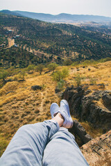 Naklejka premium Point of view of a hiker in white sneakers overlooking a picturesque nature landscape. Relaxing hiker overlooking a pretty valley. Nature