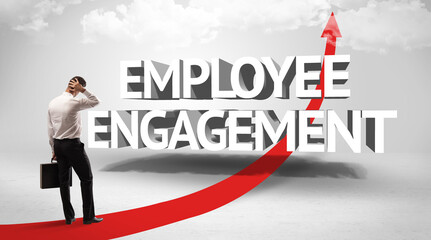 Rear view of a businessman standing in front of EMPLOYEE ENGAGEMENT inscription, successful business concept
