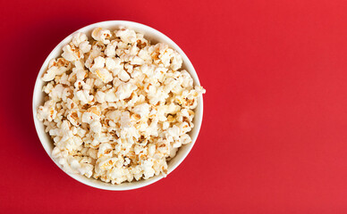 popcorn in a glass cup on a red background. View from above. Flat lay. Movie snack. Cinema and entertainment concept.