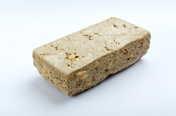 Closeup of whole piece of halva with peanuts on the white background