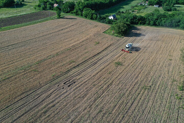 The combine harvests ripe golden wheat in the grain field. Agricultural work in summer. Drone recording. Szecső, Hungary - July 22, 2020
