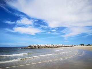 The sea on the beach and White clouds are floating in the blue sky.