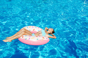 Cute smiling little girl in swimming pool with rubber ring