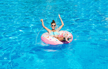 Cute smiling little girl in swimming pool with rubber ring