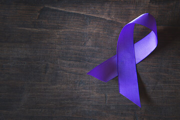 Purple ribbon on black wood background,  Pancreatic cancer, Epilepsy awareness, domestic violence awareness,  world cancer day.