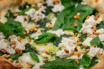 Vegetarian spinach pizza with ricotta cheese and pine nuts on a stone background.