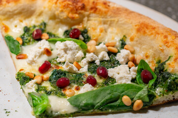 Vegetarian spinach pizza with ricotta cheese and pine nuts on a stone background.