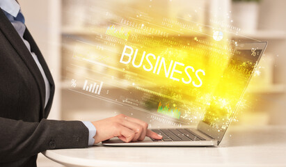 Closeup of businessman hands working on laptop with BUSINESS inscription, succesfull business concept