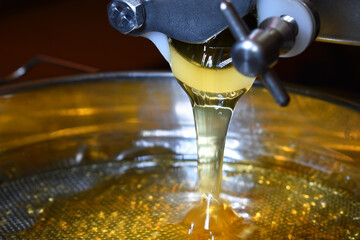 Honig rinnt aus der Honigschleuder, gelber, goldener Honig bei der Honigernte