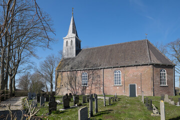 Fototapeta na wymiar Church in the little village Tjerkgaast, Friesland, The Netherlands with graveyard. The church is dedicated to Saint Augustine or Hippo