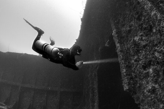 Scuba diver underwater with shipwreck 