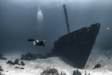 Scuba diver underwater with shipwreck 
