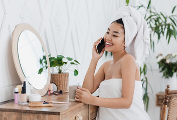 Happy asian girl talking on phone, sitting next to mirror