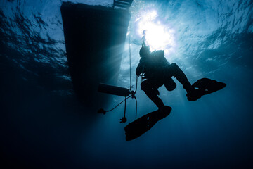 Fototapeta premium silhouette of scuba diver underwater in ocean under boat