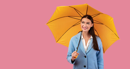 Portrait of stylish girl holding umbrella at pink studio © Prostock-studio
