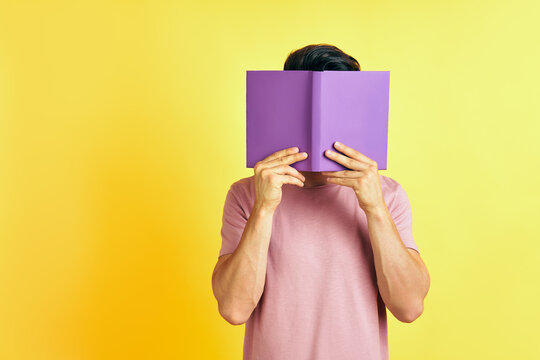 Young Man Hides His Face Behind A Book