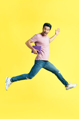 Fototapeta na wymiar Happy excited man with book jumping on yellow background
