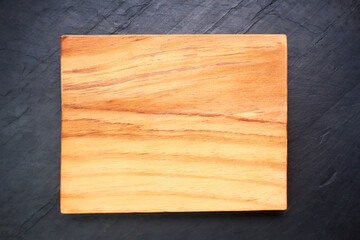 Brown wooden cutting board on black slate